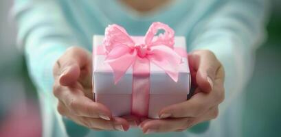 Gift Wrapped With Pink Ribbon Held by Person in Soft Lighting photo