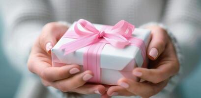 Gift Wrapped With Pink Ribbon Held by Person in Soft Lighting photo