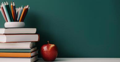 Red Apple and Colorful Pencils on Stacked Books Against a Green Wall photo