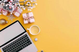Holiday Workspace With Gifts, Christmas Decorations, and Laptop on Bright Yellow Background photo
