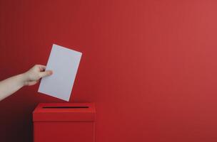 Hand Inserting Ballot Into Red Ballot Box photo