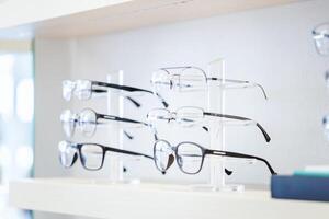Corrective eye glasses on shelf in optical store, Row of spectacles on shelves in eyeglasses shop photo