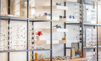 Corrective eye glasses on shelf in optical store, Row of spectacles on shelves in eyeglasses shop photo