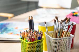 Artist's tools with brushes and different paints in a box on table photo