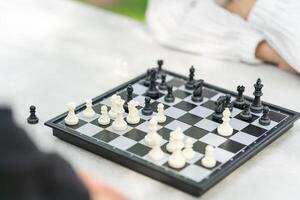 Mother playing chess with a son, Asian family relaxing hobbies playing chess in a park photo