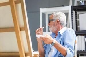 Senior man painting on canvas at home, Elderly man painting on a canvas, Happy retirement concepts photo