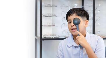 Indian kid boy choosing eyeglasses in optics store, Optometrist doing color blindness disease perception test in optical shop, Boy doing eye test checking examination with optometrist in optics store photo