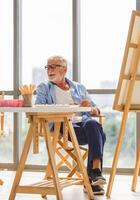 Senior man painting on canvas at home, Elderly man painting on a canvas, Happy retirement concepts photo