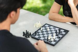 Mother playing chess with a son, Asian family relaxing hobbies playing chess in a park photo