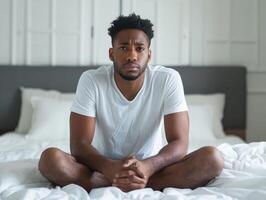 African American man sitting on bed with sad face. photo
