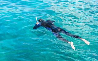 A diver in a wetsuit and mask swims in sea. Diving as a hobby. Diving lessons. Copy space. photo
