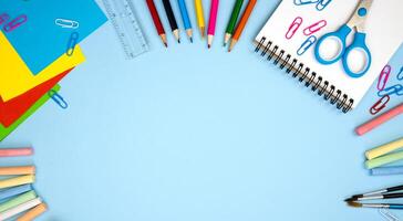 Colorful school supplies lie in the form of a frame on blue background. Back top school concept. Copy space. Flatlay composition. Top view. photo