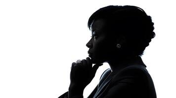 Silhouette side pose of African businesswoman with suit and hand touch chin in shadow against white background. concept of business leadership, thinking, decision photo
