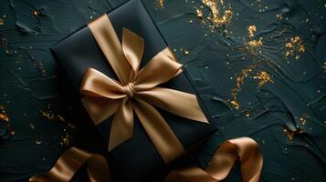 Dark gift box with elegant gold ribbon on dark background photo