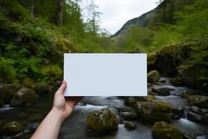 A person standing in front of a waterfall, holding a card in their hand. photo