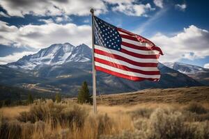 The American flag flutters proudly in front of a majestic mountain range under a clear blue sky. photo