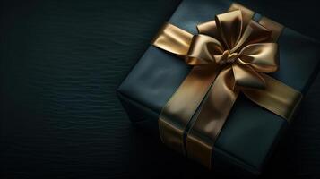 Dark gradient gift box with elegant gold ribbon on dark background photo