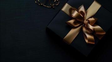 Dark black gift box with elegant gold ribbon photo