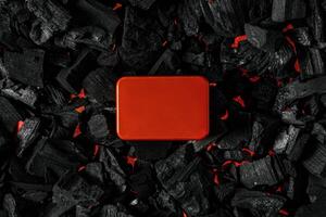 Red metal box on charcoal back. Copy space in a rectangle on a background of hot coals photo