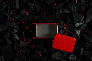 Red metal box on charcoal back. Copy space in a rectangle on a background of hot coals photo