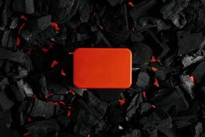 Red metal box on charcoal back. Copy space in a rectangle on a background of hot coals photo