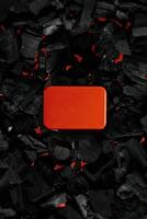 Red metal box on charcoal back. Copy space in a rectangle on a background of hot coals photo