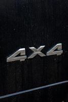 Grunge track 4x4 letters. The designation of all-wheel drive on SUVs. Unique off-road inscription in silver on a black back. photo