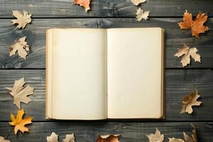 Open vintage book on an old wooden table. Withered leaves around. Dark background. photo