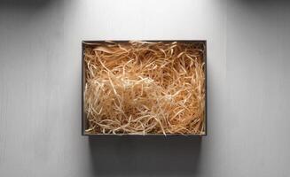 Top view of an open box with packing sawdust. Gift wrapping on the table. photo