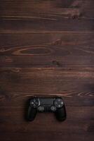 Modern black gamepad on a dark wooden background. Game concept with copy space for text. photo