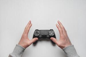 Hand hold new joystick isolated. Gamer play game with gamepad controller. Gaming man holding simulator joypad. Person with keypad joystic in arms. Sleeve hands hold toy equipment. Modern manipulator. photo