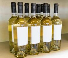 Bottles of white wine on the shelf. Wine bottles with blank labels photo