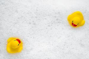 High Angle View of yellow rubber duck in bath swimming in foam water. Yellow rubber ducklings in soapy foam. photo