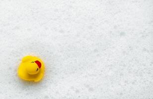 High Angle View of yellow rubber duck in bath swimming in foam water. Yellow rubber ducklings in soapy foam. photo