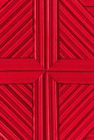 Red wooden background made of planks tightly knitted together. Simple geometric pattern with cross and diagonal lines. photo