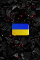 Metal rectangular box with the Ukrainian flag on a charcoal back. Copy space in a rectangle on a background of hot coals photo