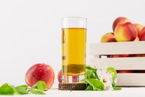 Glass of natural apple juice on a wooden podium with apples photo