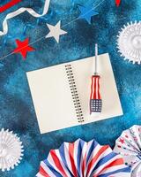 labor day flat lay with screwdriver, notepad with empty white sheets photo