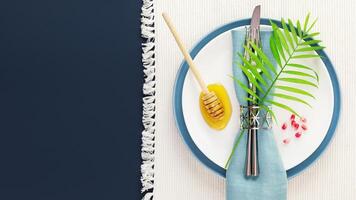 Rosh hashanah flat lay with table setting, honey and pomegranaate seeds photo
