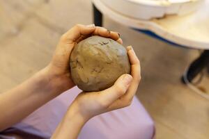 A child crushes a large piece of clay for modeling with his hands photo