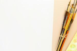 Brushes, palette and empty white sheet of paper photo