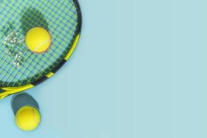 Yellow tennis balls and racket on a blue background with copy space photo