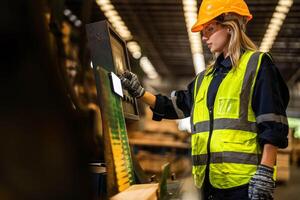 Factory engineer woman standing confident to control panel switch. Worker works at heavy machine at industry factory. worker checking timber of raw wood material. smart industry worker operating. photo