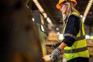 Factory engineer woman standing confident to control panel switch. Worker works at heavy machine at industry factory. worker checking timber of raw wood material. smart industry worker operating. photo
