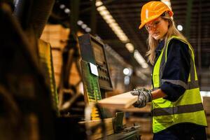 Factory engineer woman standing confident to control panel switch. Worker works at heavy machine at industry factory. worker checking timber of raw wood material. smart industry worker operating. photo