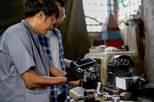 Men are inspecting steel parts for machine installation. team of teacher and student are learning to use heavy machines in steel factory. workers cooperate while doing quality control of manufactured. photo