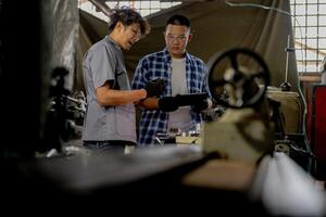 Men are inspecting steel parts for machine installation. team of teacher and student are learning to use heavy machines in steel factory. workers cooperate while doing quality control of manufactured. photo