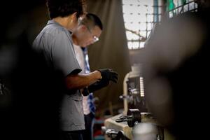 Men are inspecting steel parts for machine installation. team of teacher and student are learning to use heavy machines in steel factory. workers cooperate while doing quality control of manufactured. photo