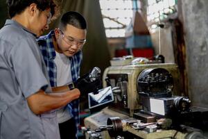 Men are inspecting steel parts for machine installation. team of teacher and student are learning to use heavy machines in steel factory. workers cooperate while doing quality control of manufactured. photo
