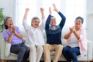 Happiness of the group females and male elderly sitting on the sofa. Senior people are talking and enjoy together at the living room. Joyful carefree retired senior friends enjoying relaxation. photo